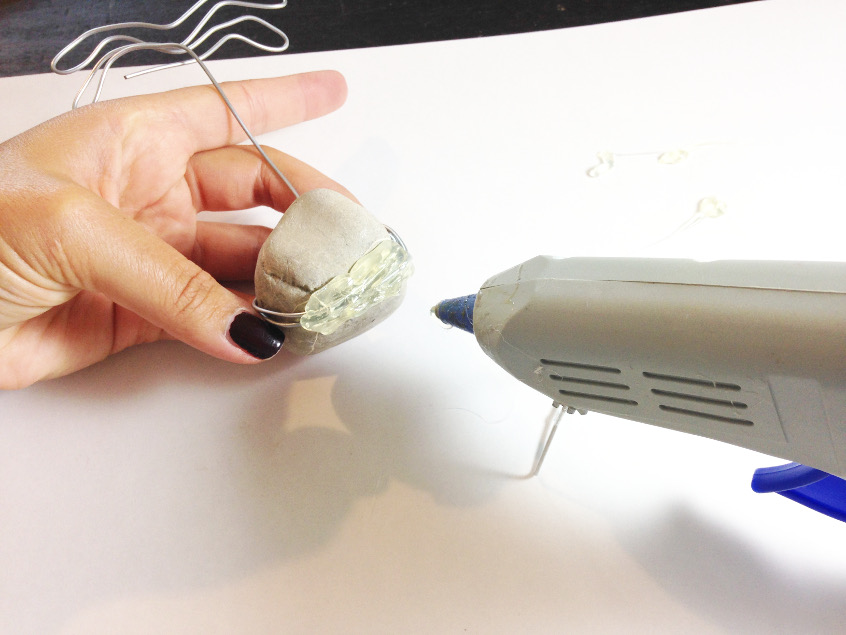 Securing the wire of your painted rock photo holder with hot glue.