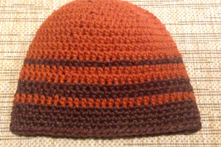 Crocheted men's hat in brown and rust stripes.