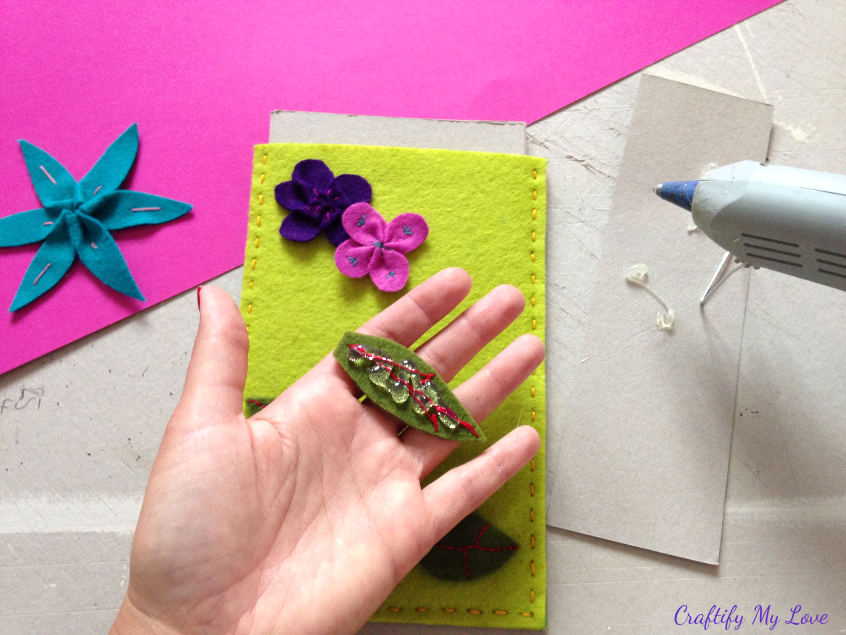 fixing felt flowers to tablet sleeve using hot glue