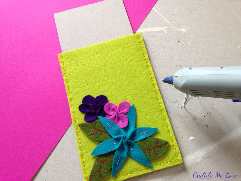 placing cardboard in hand sewn tablet sleeve before using hot glue to add felt flowers and leaves