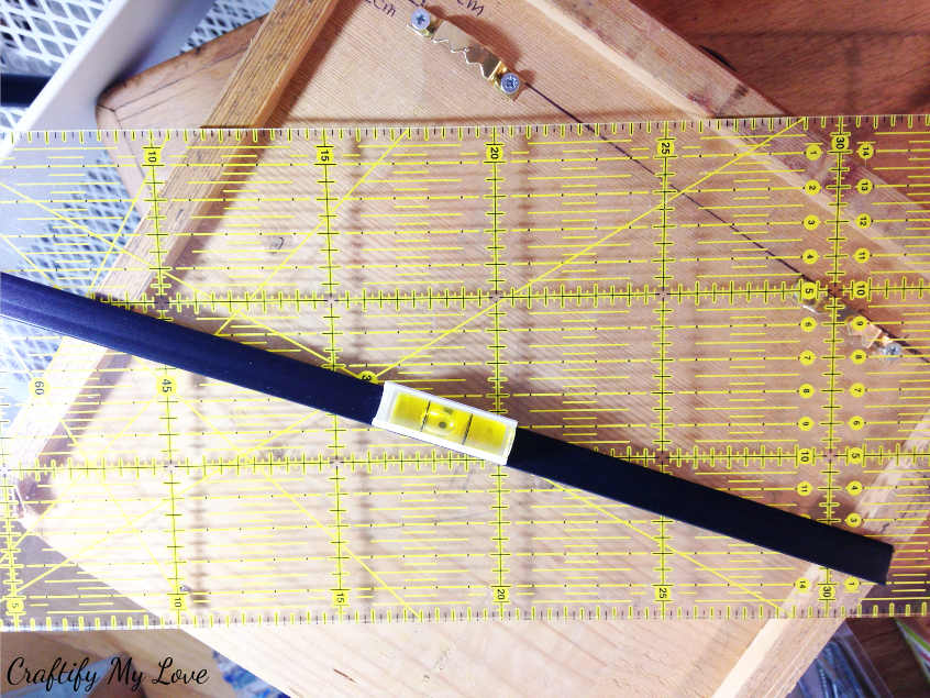 applying diy drawer shelves to wall by using a level for measuring out where to drill holes