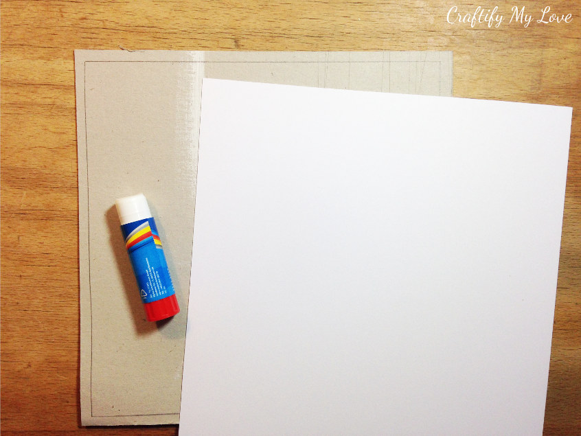 covering cardboard with white yardstick as base for melted crayons crafting inspired wall art