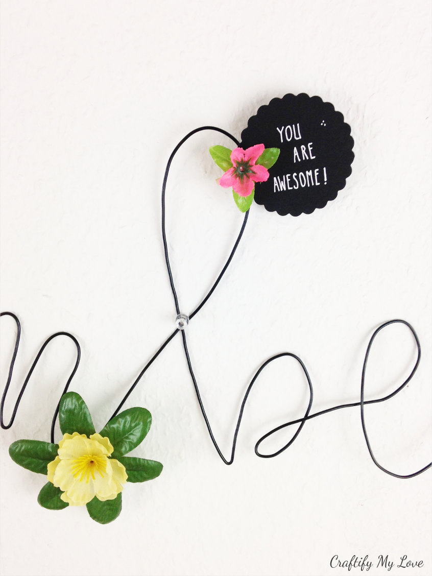 motivational quote pinned with a floral peg to wire memo board