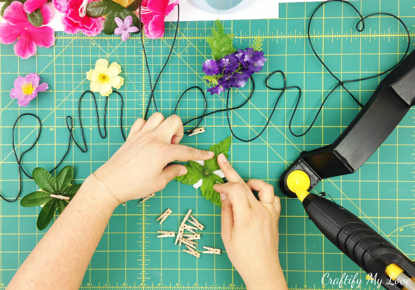 gluing faux leaves on silk flower to make spring flower memo pin that also works great for gift wrapping 