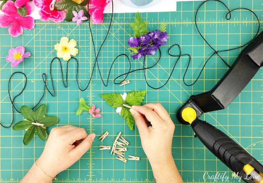 hot gluing tiny wooden clothespins to silk flowers to create reusable commando centre decor