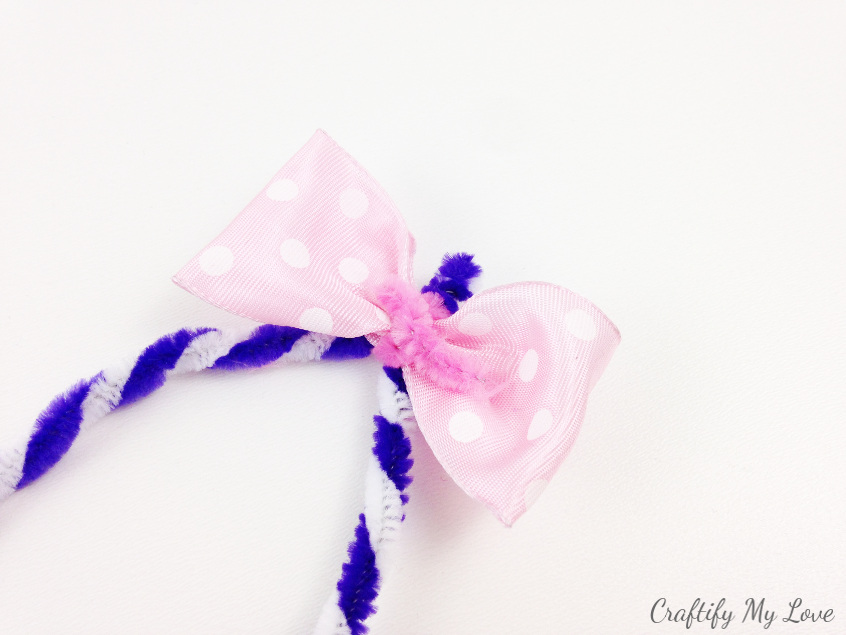 fix a pink ribbon bow to your bunny ears using a pipe cleaner