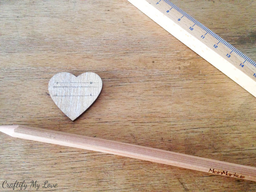 preparing little wooden hearts for DIY herb markers hand labeled 