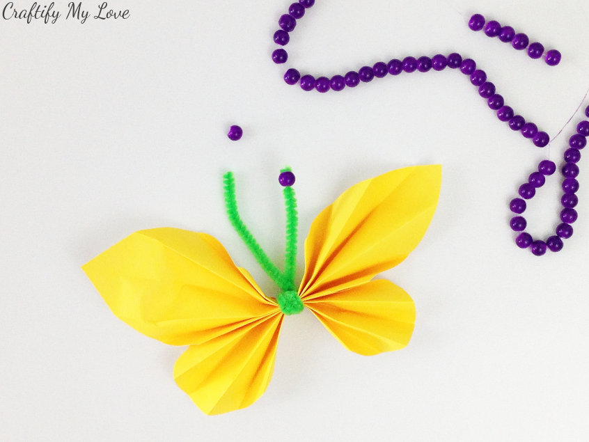 adding antennae pearls and beads for extra detail in paper butterfly kids craft