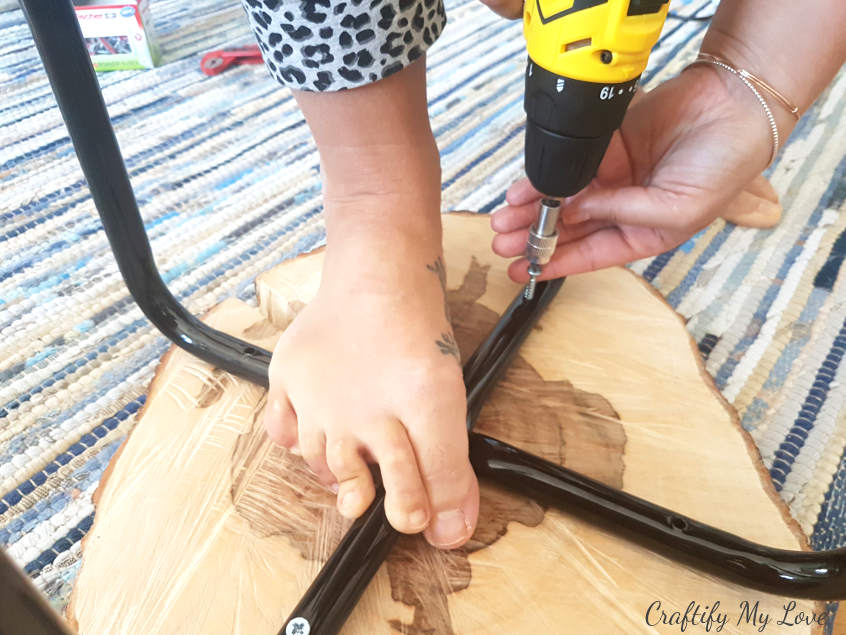 holding stool legs in place when using your drill and screws to fasten them to the natural wood handmade table