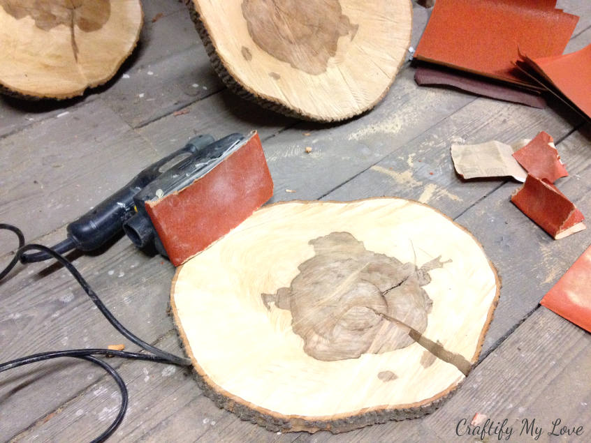 sanding down wood slices for a clean surface of side table or little stool