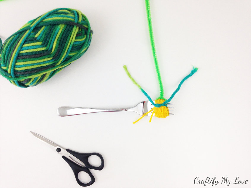 twist green wool around the flower base and secure with a tight knot
