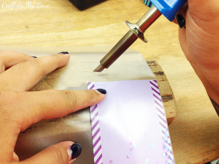 using a dremel or a fuse to seal the glitter sequins into foil in this kids craft bookmark project