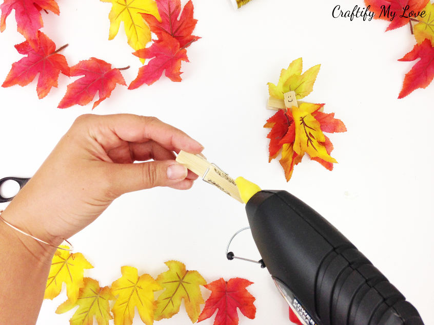 adding hot glue to apply autumn foliage to clothespin upcycling fairy craft