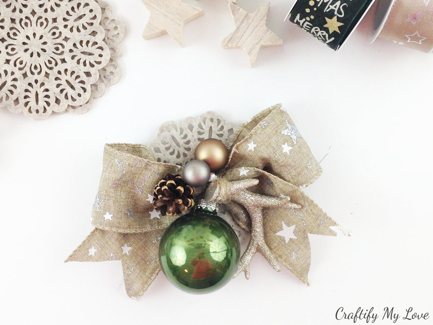 Burlap ribbon bow decorated with antlers, pine cones, christmas bulbs and a felt coaster