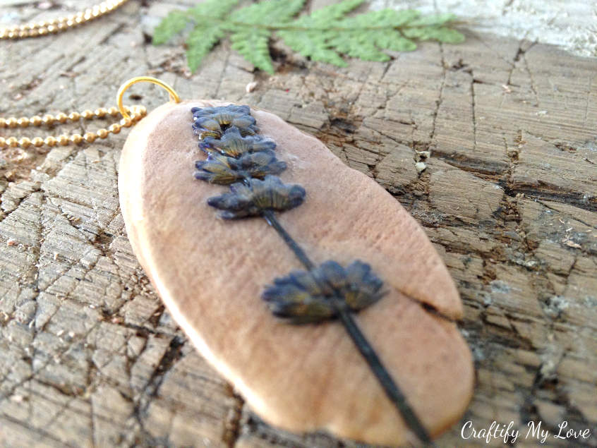 tutorial on how to make unique diy jewelry from pressed flowers in this case lavender on a wood disc