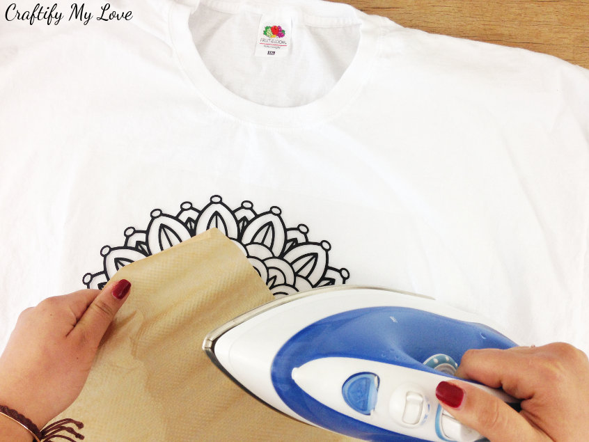 ironing the mandala design on your DIY creative t-shirt idea by using iron on vinyl, baking sheet and an iron