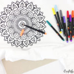 start filling in or colouring the mandala design using fabric markers to create a unique kids t-shirt as a summer activity for a rainy day