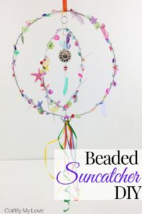 Sparkly seaquined and beaded suncatcher hoop mobile to add a pop of colour to your garden. Click through for a detailed tutorial on how to make this wind spinner for little money. #craftifymylove #suncatcher #windwpinner #windchime #DIYgardendecor #summercraft #DIYhomedecor